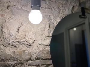 une lampe suspendue à un mur en pierre avec un miroir dans l'établissement Altrelli B&B, à Corato