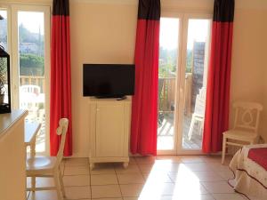a living room with red curtains and a flat screen tv at Maison Duplex 8 Pers avec Terrasse, 3 Ch, Parking Gratuit, Animaux Admis, Accès Piscine - FR-1-382-128 in Grospierres