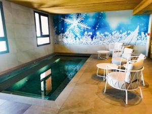 a swimming pool with chairs and tables in a room at Résidence LES CRISTAUX in Arc 1800