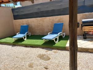 dos sillas azules sentadas en un parche de hierba en Studio indépendant dans villa, en Néffiès
