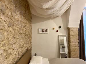 - une chambre avec un mur en pierre, un lit et un miroir dans l'établissement Altrelli B&B, à Corato