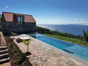 a house with a swimming pool next to the ocean at CASAS DO LARANJO- Cottages & Infinity Pool in Gaula