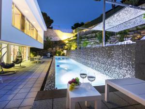 two glasses of wine on a table next to a swimming pool at Holiday Home Nathalie by Interhome in Sant Antoni de Calonge