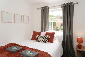 a bedroom with a bed with red pillows and a window at Modern 3BRhouse close to town with free parking in Kent