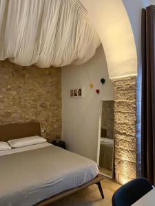 - une chambre avec un lit et un mur en pierre dans l'établissement Altrelli B&B, à Corato