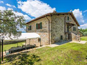 un antiguo edificio de piedra con bancos delante en Holiday Home La Querciolaia by Interhome en Pieve a Presciano