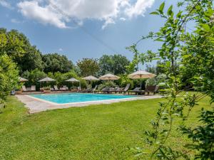 a swimming pool with chairs and umbrellas at Holiday Home Carola by Interhome in Cinigiano