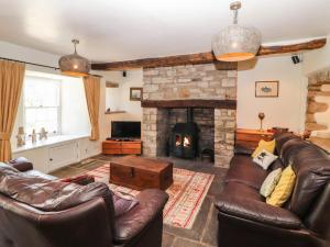 a living room with leather furniture and a stone fireplace at Roger Pot in Sedbergh