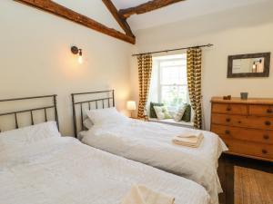two beds in a bedroom with a dresser and a window at Roger Pot in Sedbergh