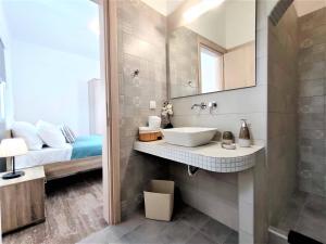 Un baño con lavabo, cama y espejo. en Studio Elpida Santorini, en Vóthon