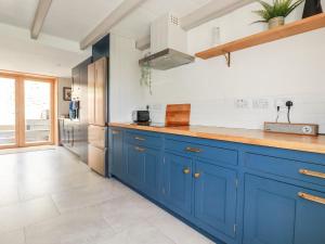 a kitchen with blue cabinets and a refrigerator at Greenbank in Perranporth
