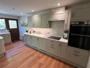 a kitchen with white cabinets and wooden floors at Willow Brook in Blandford Forum