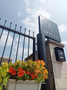 a sign for a hotel with flowers in a planter at Hotel Porta Rivera in LʼAquila