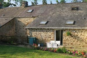 una casa de ladrillo con 2 sillas blancas y una ventana en Chez Hervé, en Saint-Mars-sur-Colmont