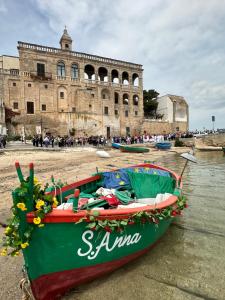 a green boat sitting in the water in front of a building at Domus Angela in Polignano a Mare