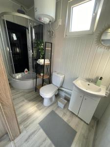 een badkamer met een toilet, een wastafel en een bad bij Domki letniskowe Bali in Jezierzany