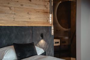 1 dormitorio con 1 cama con pared de madera en Hotel Alpenrose en Carezza al Lago