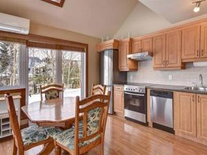 a kitchen with a wooden table and a dining room at Bright Condo near the Lake by GLOBALSTAY in Mont-Tremblant