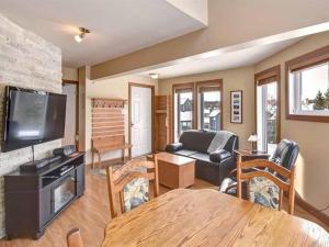 a living room with a couch and a tv and a table at Bright Condo near the Lake by GLOBALSTAY in Mont-Tremblant