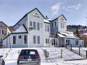 a car parked in front of a house in the snow at Bright Condo near the Lake by GLOBALSTAY in Mont-Tremblant