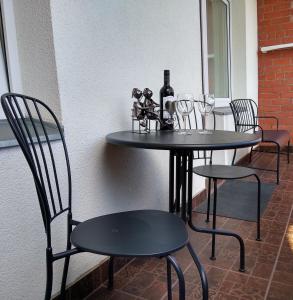 Sunrise Apartment في مادونا: طاولة سوداء وكراسي عليها كؤوس للنبيذ
