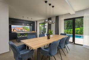 a dining room with a wooden table and blue chairs at Villa Olea by IstriaLux in Šumber