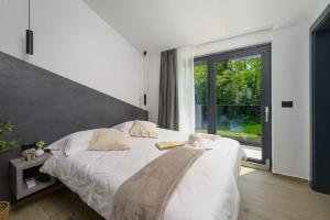 a bedroom with a white bed and a large window at Villa Olea by IstriaLux in Šumber