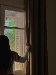 カイロにあるlovely apartment in Zamalekの若い女の子が窓の外を見ている