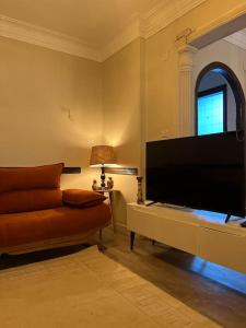 lovely apartment in Zamalek في القاهرة: غرفة معيشة مع أريكة وتلفزيون بشاشة مسطحة