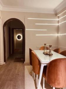 lovely apartment in Zamalek في القاهرة: غرفة طعام مع طاولة بيضاء وكراسي