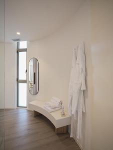 ein weißes Zimmer mit einem Spiegel und einer Bank in der Unterkunft Retiro Costiña Wellness&villas in Santa Comba