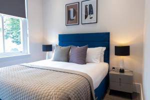a bedroom with a large bed with a blue headboard at Premier London Apartments Near Camden markets & very close to tube stations by Belvilla in London