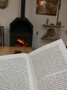 Ein offenes Buch liegt auf einem Tisch neben einem Kamin. in der Unterkunft Orange House in Trnovo
