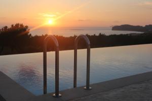 a pool with two metal bars in front of a sunset at Diamond Star Hotel in Falasarna