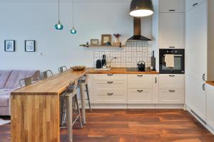 a kitchen with white cabinets and a wooden counter top at Apartament Pod 6 in Uniejow