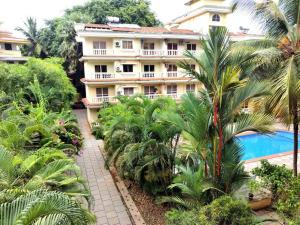 an apartment building with palm trees and a swimming pool at #vrabode 1BHK apartment w Pool at Seacoast Retreat Varca in Talaulim
