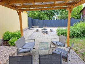 a patio with chairs and tables and a wooden pergola at Belvárosi Lux Apartman in Vásárosnamény