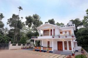 une maison blanche avec une véranda et une allée. dans l'établissement Greenfield Homestay, à Vythiri