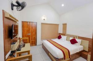 Dormitorio con cama, escritorio y TV en Greenfield Homestay en Vythiri