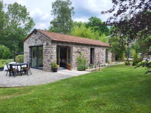 un edificio in pietra con tavolo e sedie in cortile di Out & LODGE Les Spirous a Les Géronsarts