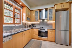 a kitchen with wooden cabinets and a stainless steel refrigerator at Harmony villa - Ioannina castle in Ioannina