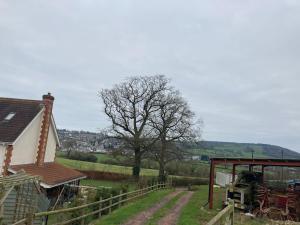 a farm with a house and a tree and a dirt road at Park gate house farm holidays, Colyton-‘Elizabeth in Colyton