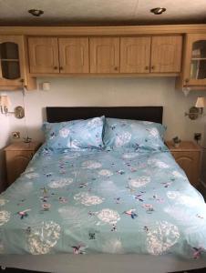 a bed with a blue comforter with butterflies on it at Park gate house farm holidays, Colyton-‘Elizabeth in Colyton