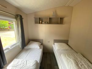 2 łóżka w małym pokoju z oknem w obiekcie Mobilheim Wattwurm mit Veranda am Kransburger See 555 w mieście Kransburg