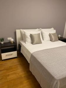 une chambre avec un grand lit avec des draps et des oreillers blancs dans l'établissement Apartments Marija, à Biograd na Moru