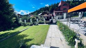 a yard with a house and a grassy field at Pensiunea Luminita in Buşteni