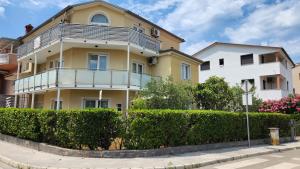 a yellow house with a balcony on a street at Villa Darinka in Fažana