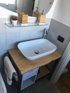 un lavabo blanc sur une table en bois dans une salle de bains dans l'établissement Casa nel Borgo vicinissima al centro di Torino, à Turin