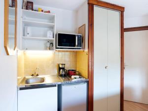 eine kleine Küche mit einer Spüle und einer Mikrowelle in der Unterkunft Studio les chalets du soleil by Interhome in Saint-Gervais-les-Bains
