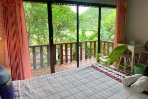 a bedroom with a bed and a view of a deck at Phuchomjan Resort in Mae Hong Son